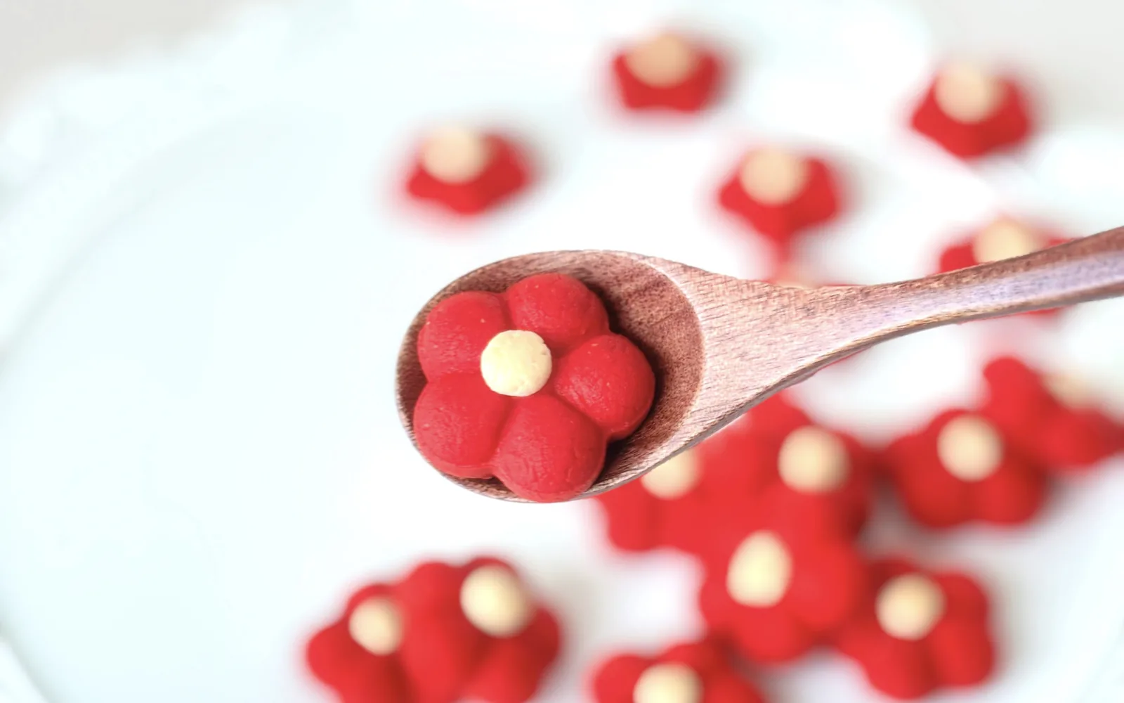 Cookies hình hoa đỏ trên thìa gỗ và đĩa ren trắng